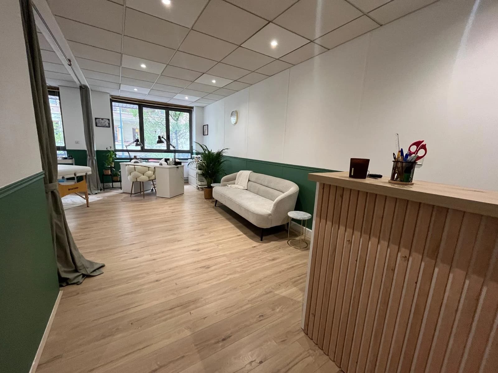 L’entrée de l’institut, avec le comptoir en tasseaux de bois et le salon au fond